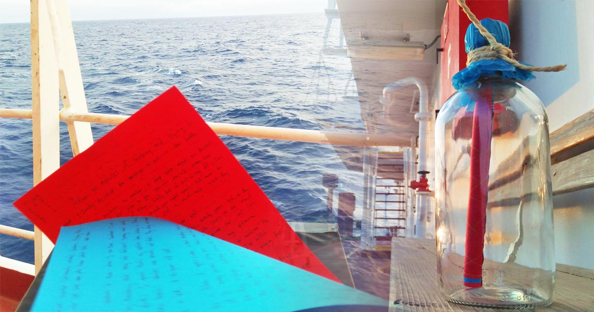 A message written in red and blue paper with a view of the ocean and a clear bottle with the letters rolled inside.