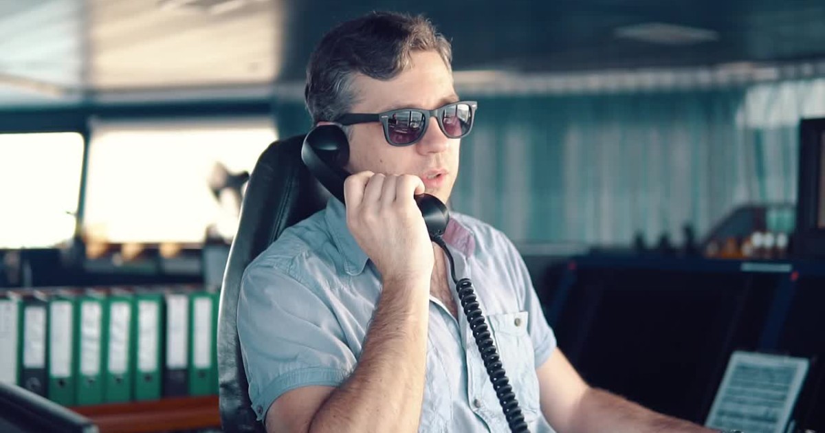 A ship officer inside the bridge using a telephone as he calls and notifies the master about important matters.